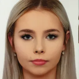 Portret młodej kobiety z blond włosami i niebieskimi oczami, na białym tle. Widoczne delikatne kolczyki.