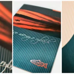 Trzy kadry z projektu graficznego: zbliżenie na tekst 'Dużo wiemy o rybach' na tle zachodzącego słońca i pionowych pasków, oraz faktura ciemnozielonego papieru z wytłoczonym motywem ryby.