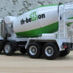 Miniatura betonomieszarki z Radomia, z zielonym pasem i logo 'th-beton' na białym bębnie, ustawiona na drewnianej powierzchni.