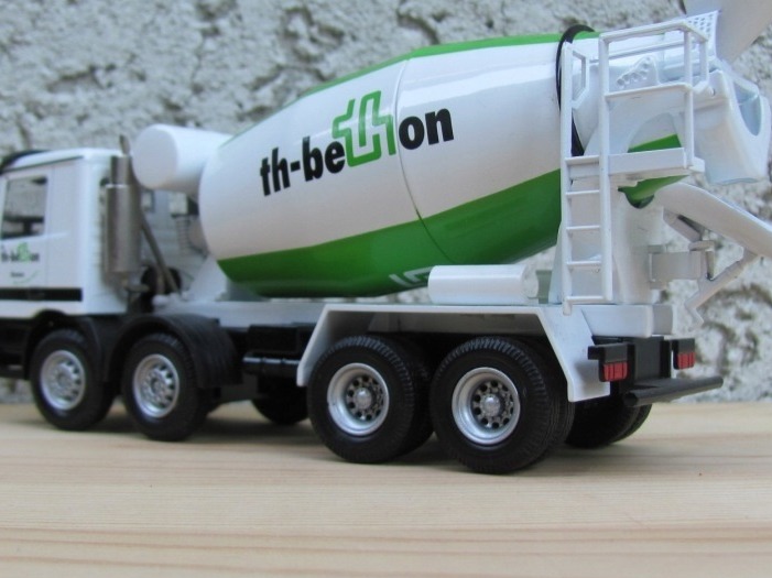 Miniatura betonomieszarki z Radomia, z zielonym pasem i logo 'th-beton' na białym bębnie, ustawiona na drewnianej powierzchni.