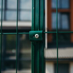 Metfence - Fragment zielonego ogrodzenia panelowego z widocznym mocowaniem na tle budynku.