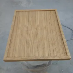 Surowy, drewniany blat z wyraźnym usłojeniem, w trakcie obróbki, osłonięty folią ochronną.