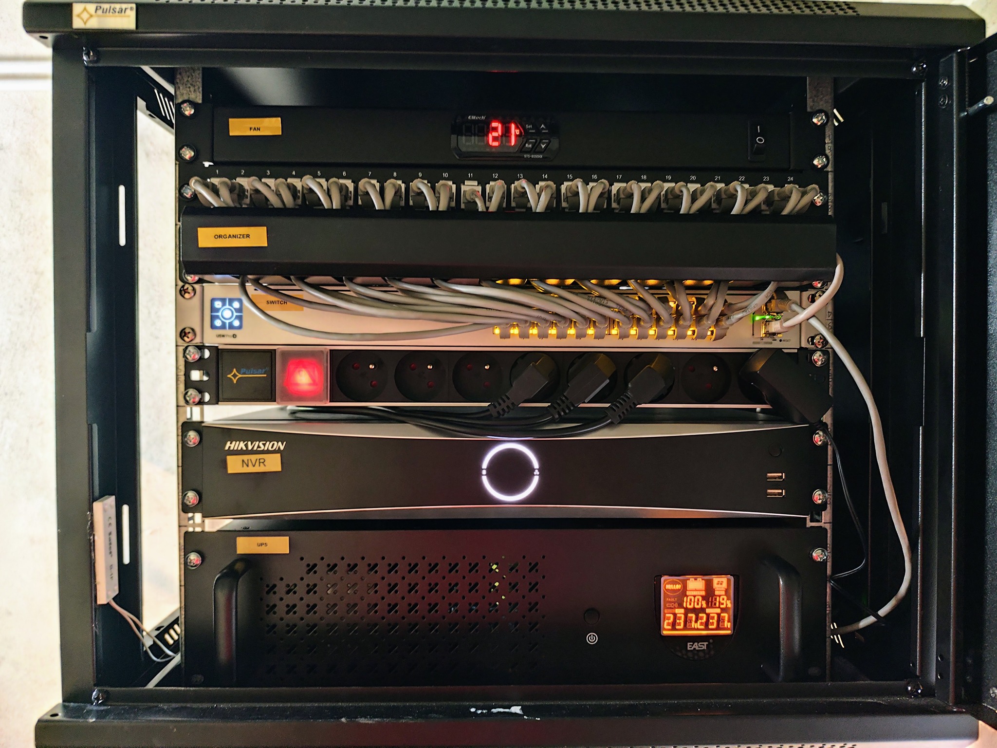 Szafa Rack z panelem chłodzącym, patch panelem, organizerem kablowym, switchem PoE, listwą zasilającą, rejestratorem CCTV i UPS, zamontowana wewnątrz obudowy.