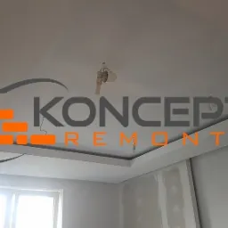 Sufit podwieszany z oświetleniem w trakcie prac wykończeniowych, widoczne logo firmy nałożone na zdjęcie.