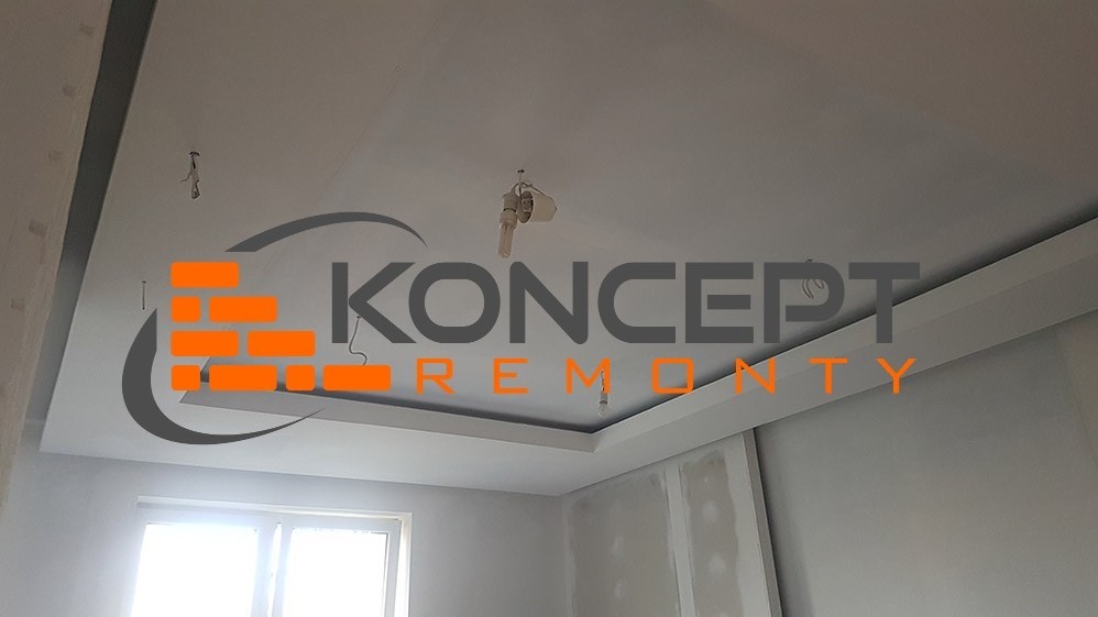 Sufit podwieszany z oświetleniem w trakcie prac wykończeniowych, widoczne logo firmy nałożone na zdjęcie.