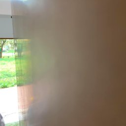 M&P Solid - Świeżo pomalowana ściana w odcieniach beżu, widok z wnętrza pomieszczenia na zieleń ogrodu przez okno z roletami.