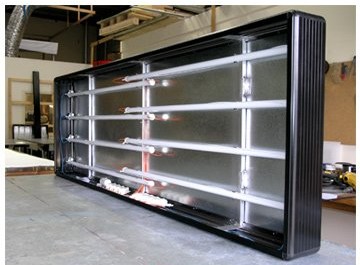 Wewnętrzna konstrukcja podświetlanego kasetonu reklamowego z zamontowanymi świetlówkami, widoczne przewody i elementy instalacji elektrycznej.