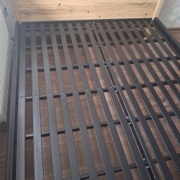 OLTECH Adam Oleksy - Rama łóżka z metalowymi szczebelkami i drewnianym zagłówkiem, widoczna z góry pod kątem, z elementami montażowymi.