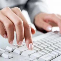 Dłonie kobiety piszącej na klawiaturze komputera w Drogomyślu, widoczne paznokcie pomalowane na jasny kolor.