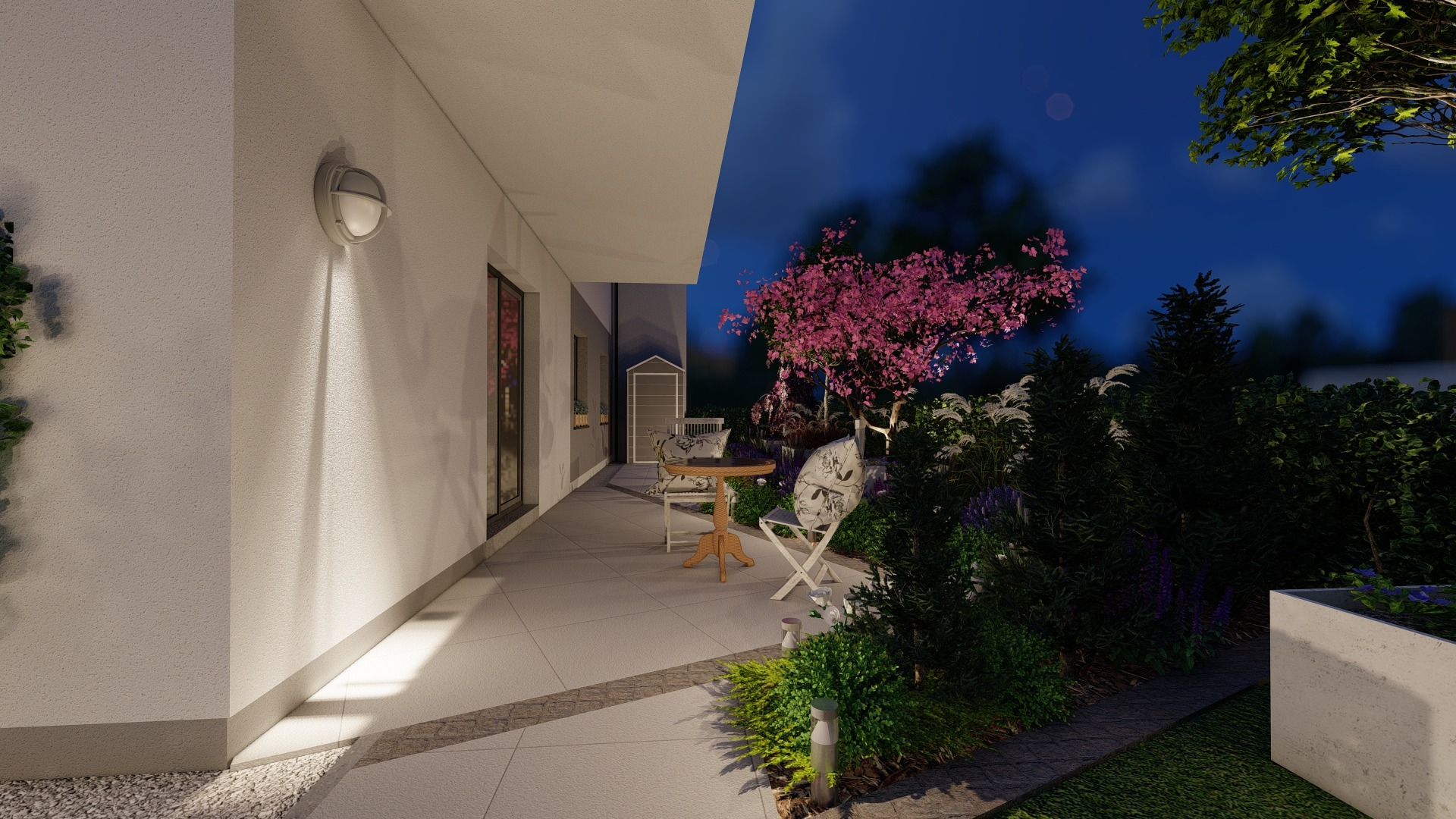 Wieczorny widok na taras z krzesłami i stolikiem, otoczony bujną roślinnością z kwitnącym drzewem na tle nocnego nieba.