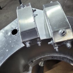 Mobilne Usługi Ślusarskie ŁUKASZ PILACZYŃSKI - Dwa spawane, aluminiowe zbiorniki z gwintowanymi króćcami, leżące na aluminiowej konstrukcji z widocznymi spawami.