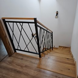 Mobilne Usługi Ślusarskie ŁUKASZ PILACZYŃSKI - Nowoczesne schody drewniane z czarną, geometryczną balustradą metalową i drewnianym poręczą. Widok z góry, oświetlenie punktowe.