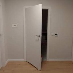 REKER Jarosław Ośliźlok - Trzy białe drzwi wewnętrzne w jasnym korytarzu, jedne z nich są otwarte, ukazując wnętrze pomieszczenia.