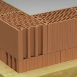 Fragment ściany z pustaków ceramicznych Porotherm na warstwie izolacji termicznej, widoczne charakterystyczne perforacje i połączenia na pióro i wpust.