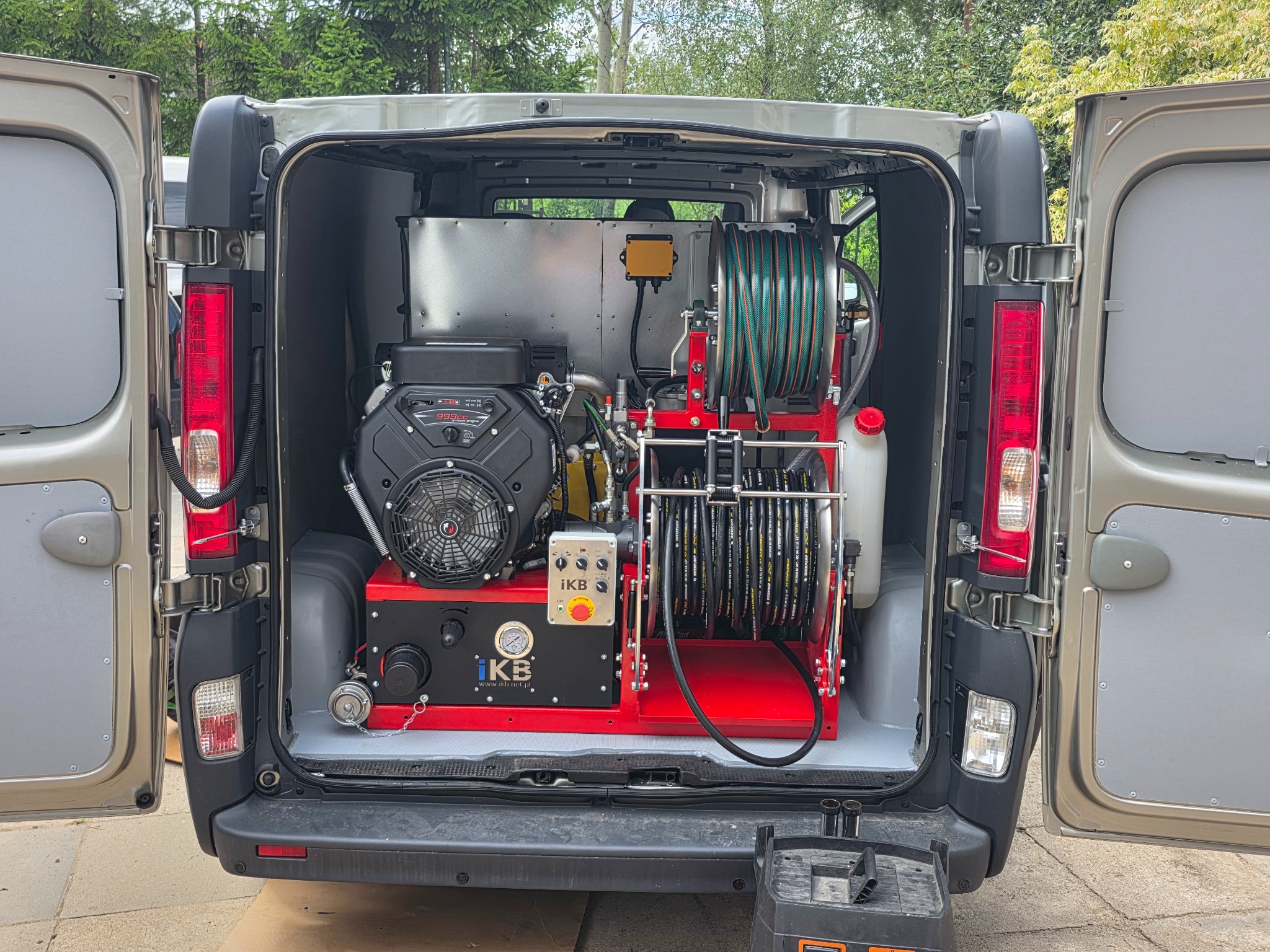 Wyposażenie pojazdu do czyszczenia kanalizacji: silnik, zbiornik, zwijadła z wężami. Widok z tyłu otwartego samochodu dostawczego z zamontowanym sprzętem.