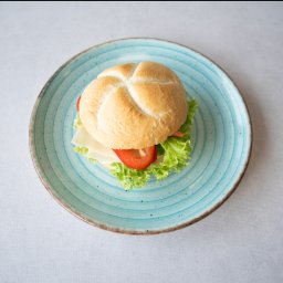 Canappka - Kanapka z serem, pomidorem i sałatą na turkusowym talerzu z Rzeszowa, ujęcie z góry.