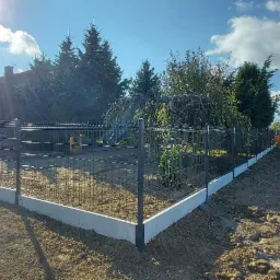 Nowoczesne ogrodzenie panelowe z podmurówką betonową, Łęczna, widok na posesję i otwarty teren, słoneczny dzień.