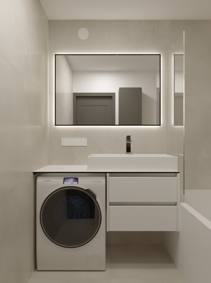 Nowoczesna łazienka w beżowej kolorystyce z pralką obok umywalki i podświetlanym lustrem w czarnej ramie.