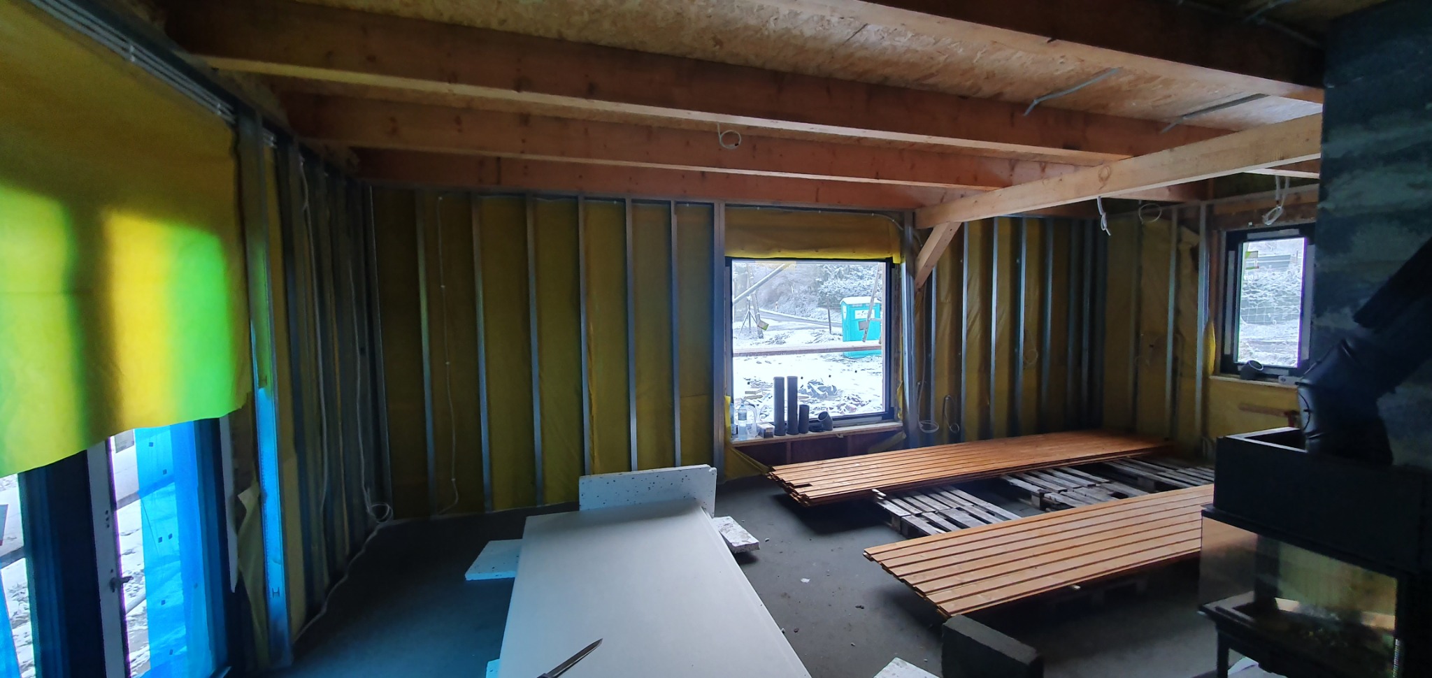 Wnętrze w trakcie ocieplania poddasza: widoczne metalowe profile, wełna mineralna, płyty karton-gips oraz przygotowane deski podłogowe.