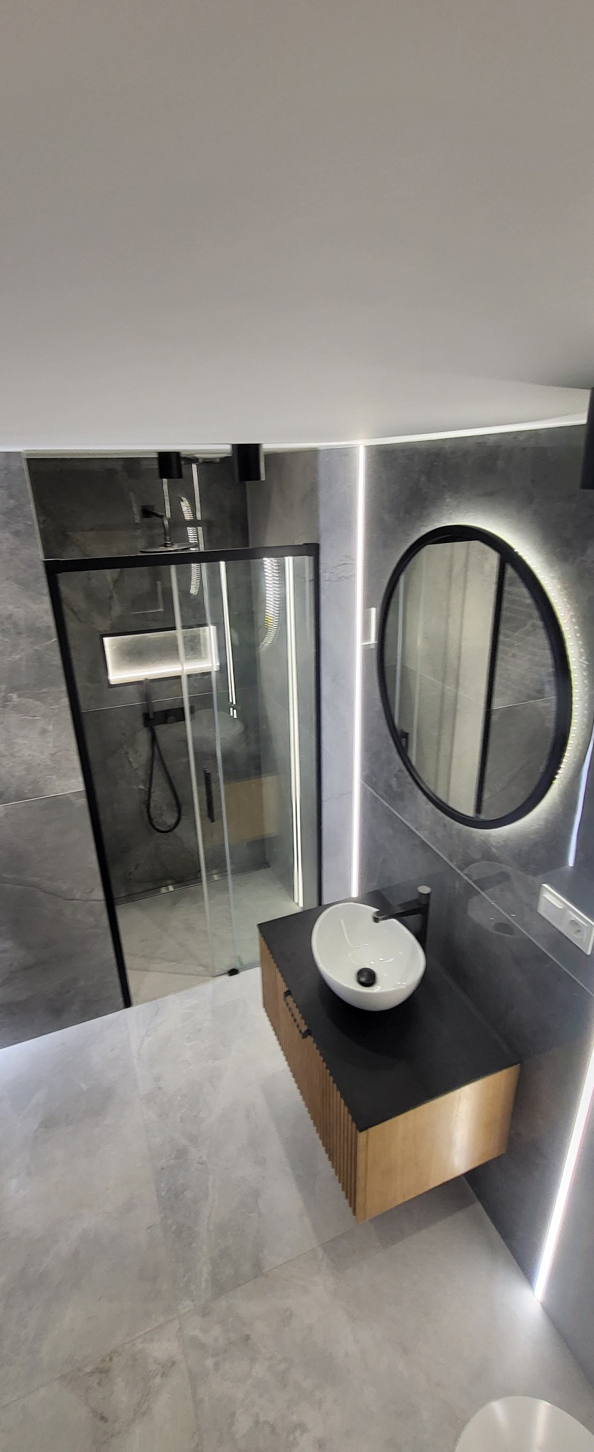 Nowoczesna łazienka w Koninie z szarą armaturą, oświetlonym lustrem owalnym i kabiną prysznicową typu walk-in.