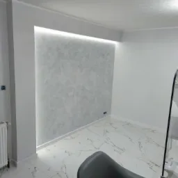 Wykończone wnętrze: ściana z dekoracyjną fakturą podświetloną LED, marmurowe płytki podłogowe i grzejnik.