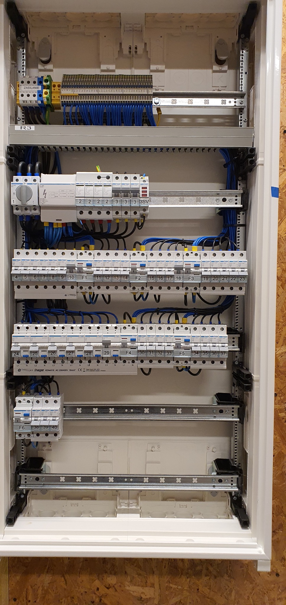 Rozdzielnica elektryczna z zamontowanymi bezpiecznikami, przewodami i listwami zaciskowymi, widok z bliska.