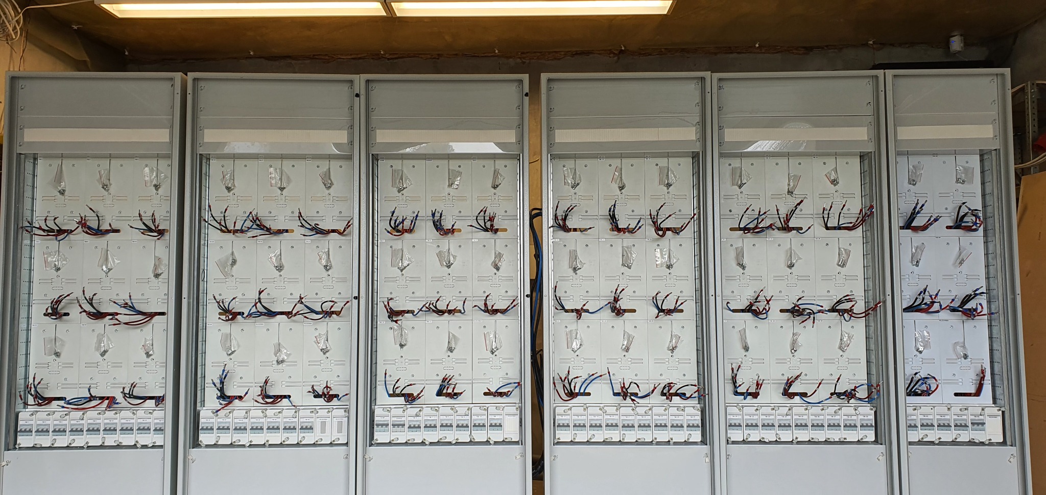 Rozdzielnice elektryczne w trakcie montażu przewodów, widoczne zabezpieczenia i schemat rozmieszczenia.