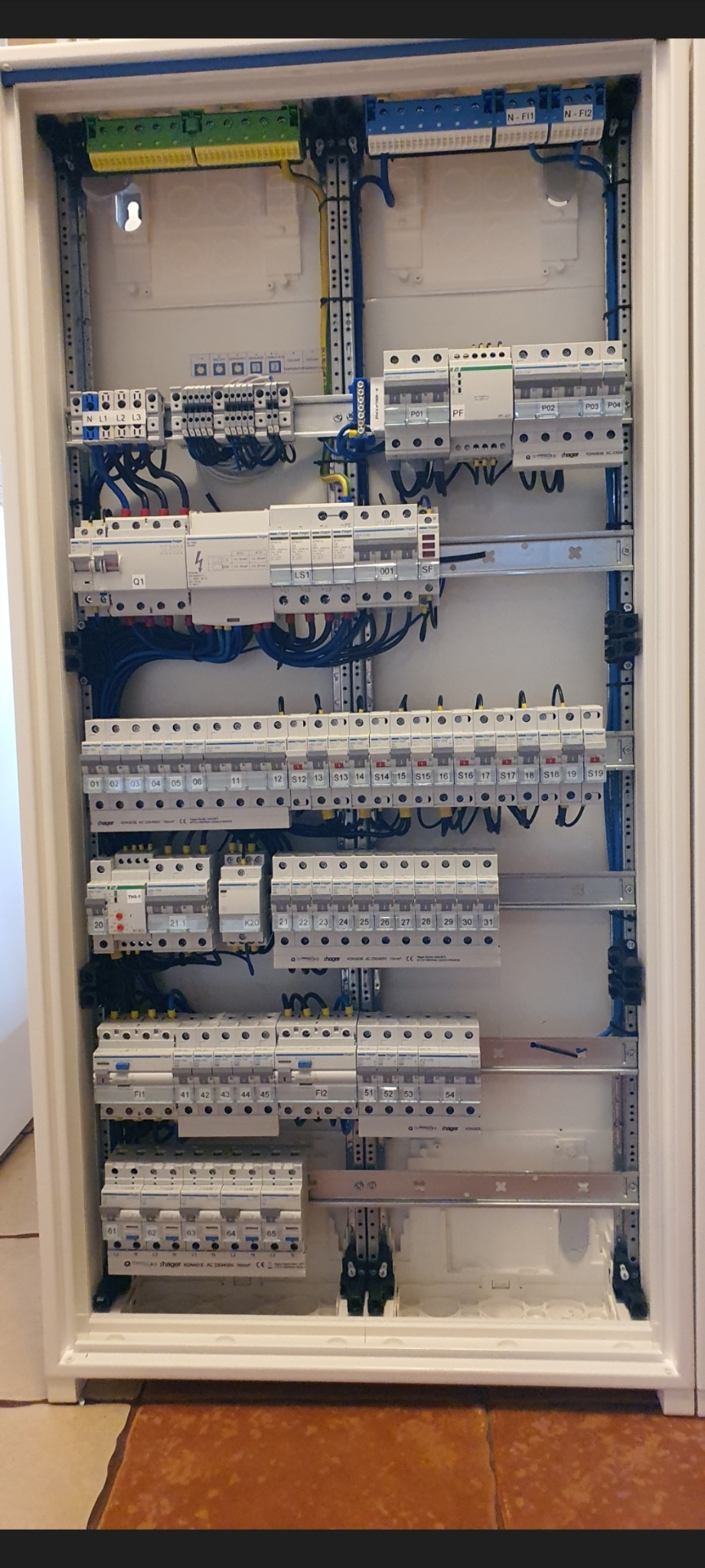 Rozdzielnica elektryczna z zainstalowanymi bezpiecznikami i przewodami, widok z bliska na uporządkowany układ elementów.