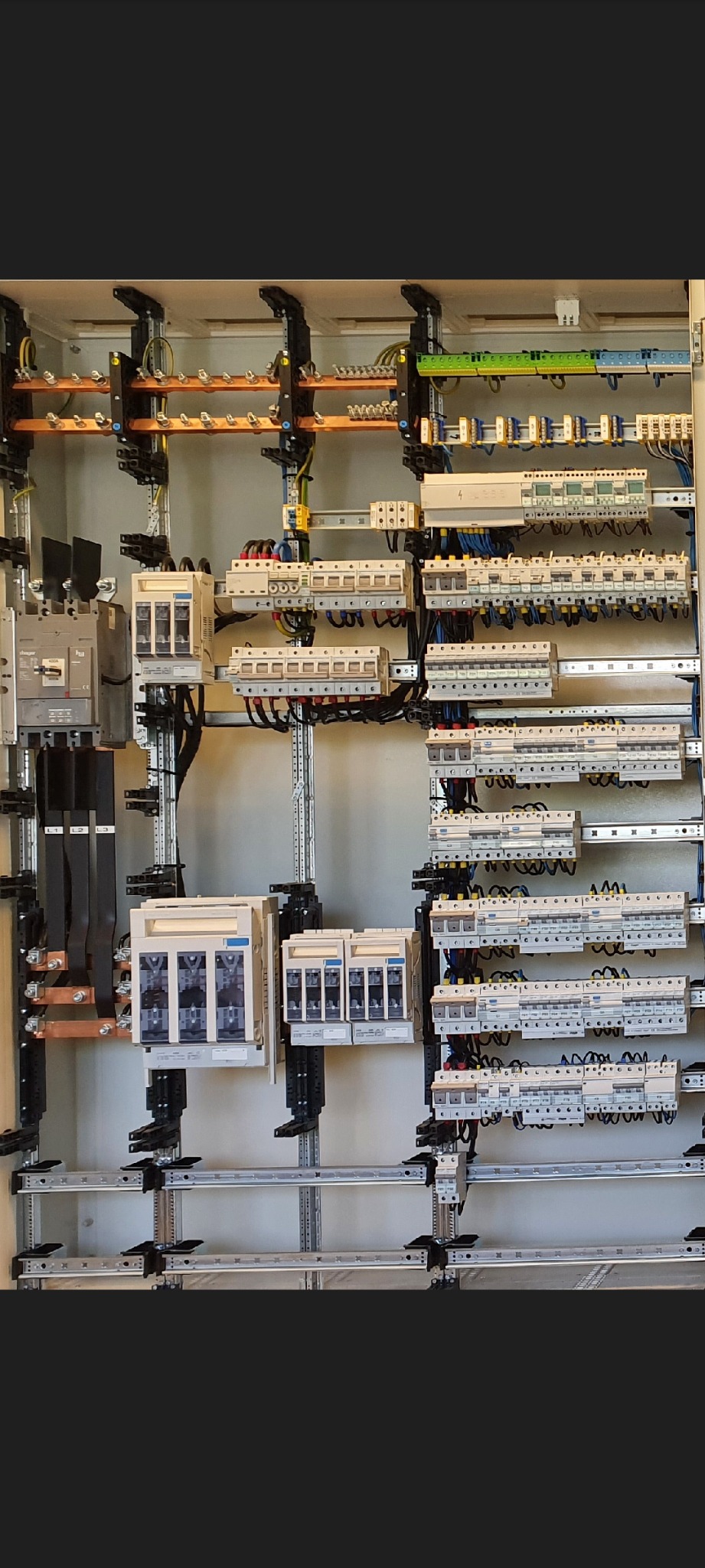 Rozbudowana, profesjonalnie zamontowana skrzynka rozdzielcza z licznymi zabezpieczeniami i przewodami, umieszczona na metalowej konstrukcji nośnej.