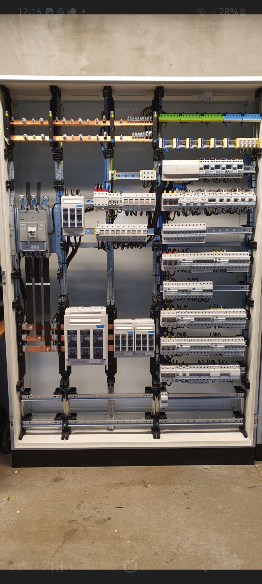 Rozdzielnica elektryczna z zamontowanymi bezpiecznikami, wyłącznikami i okablowaniem, widok z przodu, szyna montażowa z elementami mocującymi.