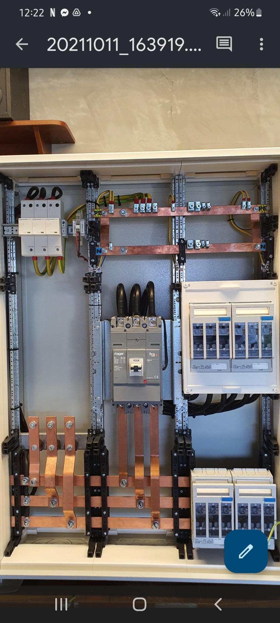 Otwarta szafa elektryczna z zainstalowanymi bezpiecznikami, wyłącznikiem 400A Hager i miedzianymi szynami zbiorczymi, widoczne przewody i elementy montażowe.