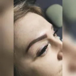 Zbliżenie na twarz kobiety po zabiegu pigmentacji brwi metodą pudrową, widoczne sztuczne rzęsy i naturalne piegi.