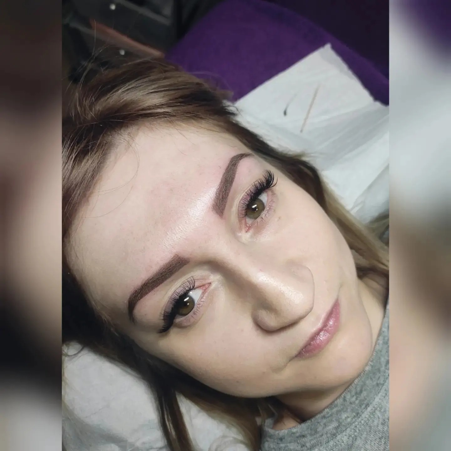 Kobieta leżąca na plecach z widocznymi, świeżo wykonanymi brwiami permanentnymi i przedłużonymi rzęsami, uchwycona z góry.