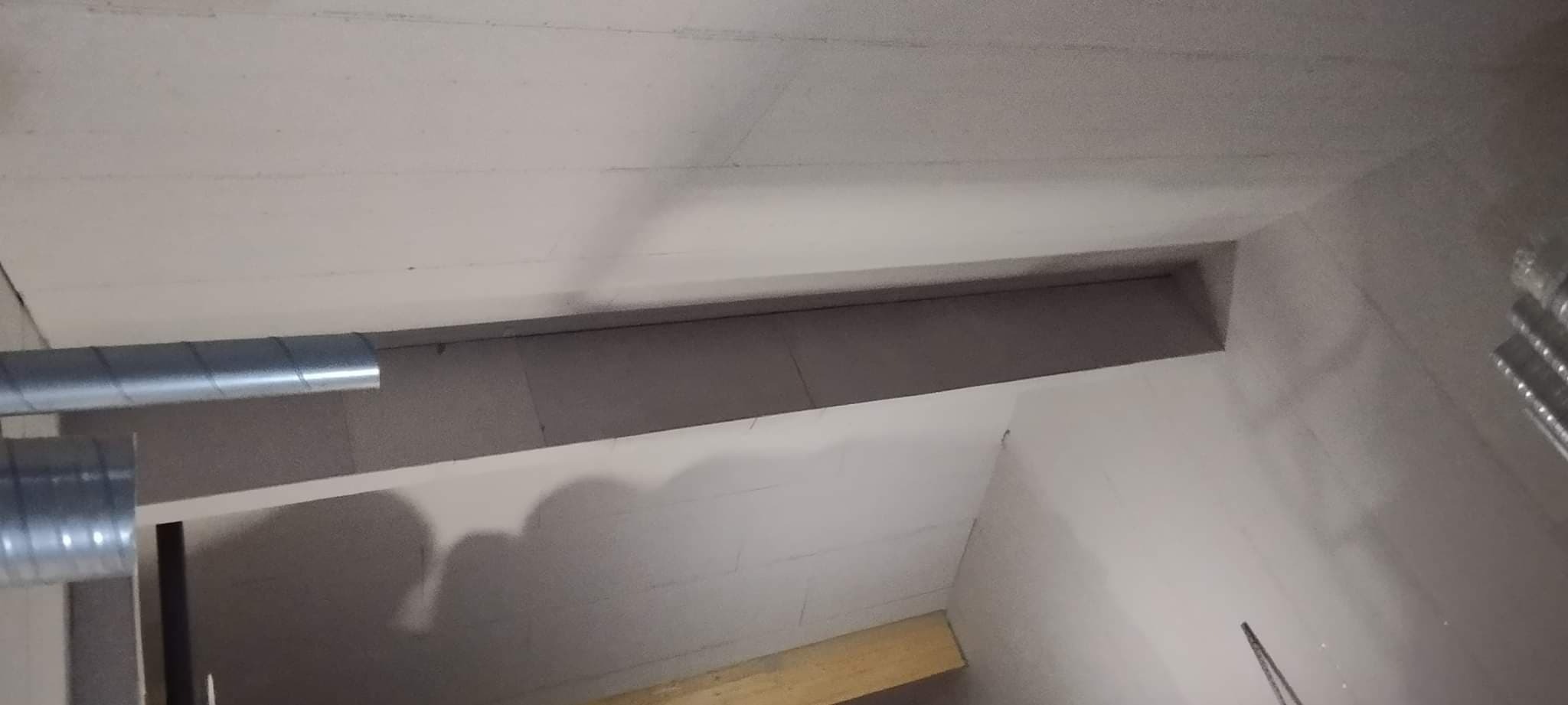 Sufit podwieszany z widocznymi przewodami wentylacyjnymi w trakcie montażu.