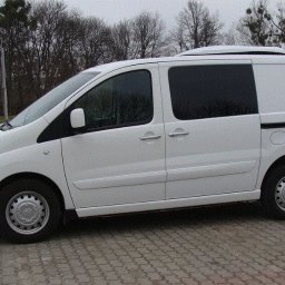 FORMAT 74 Maciej Dranicki - Biały furgon z nadbudówką chłodniczą na dachu, zaparkowany na kostce brukowej, widok z boku.