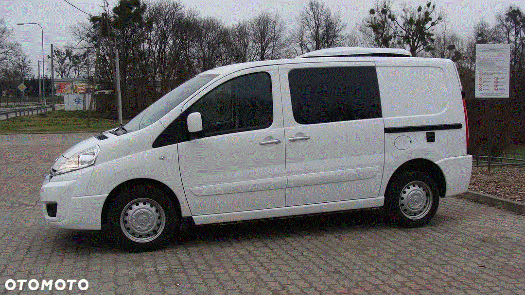 Biały furgon z nadbudówką chłodniczą na dachu, zaparkowany na kostce brukowej, widok z boku.