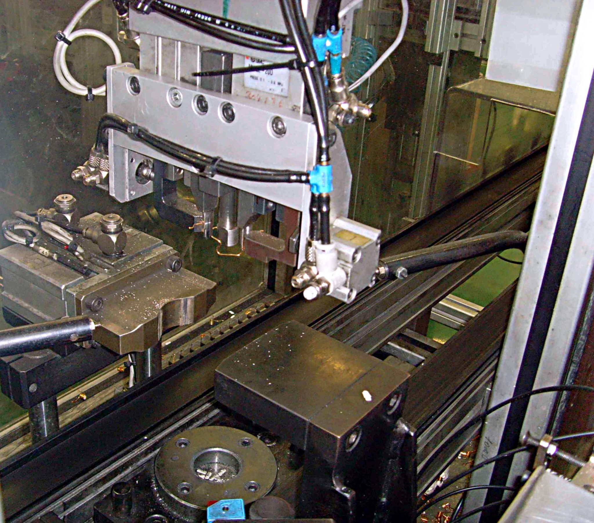 Szczegółowe ujęcie automatycznej spawarki z widocznymi elementami mocującymi, przewodami pneumatycznymi i elektrodami