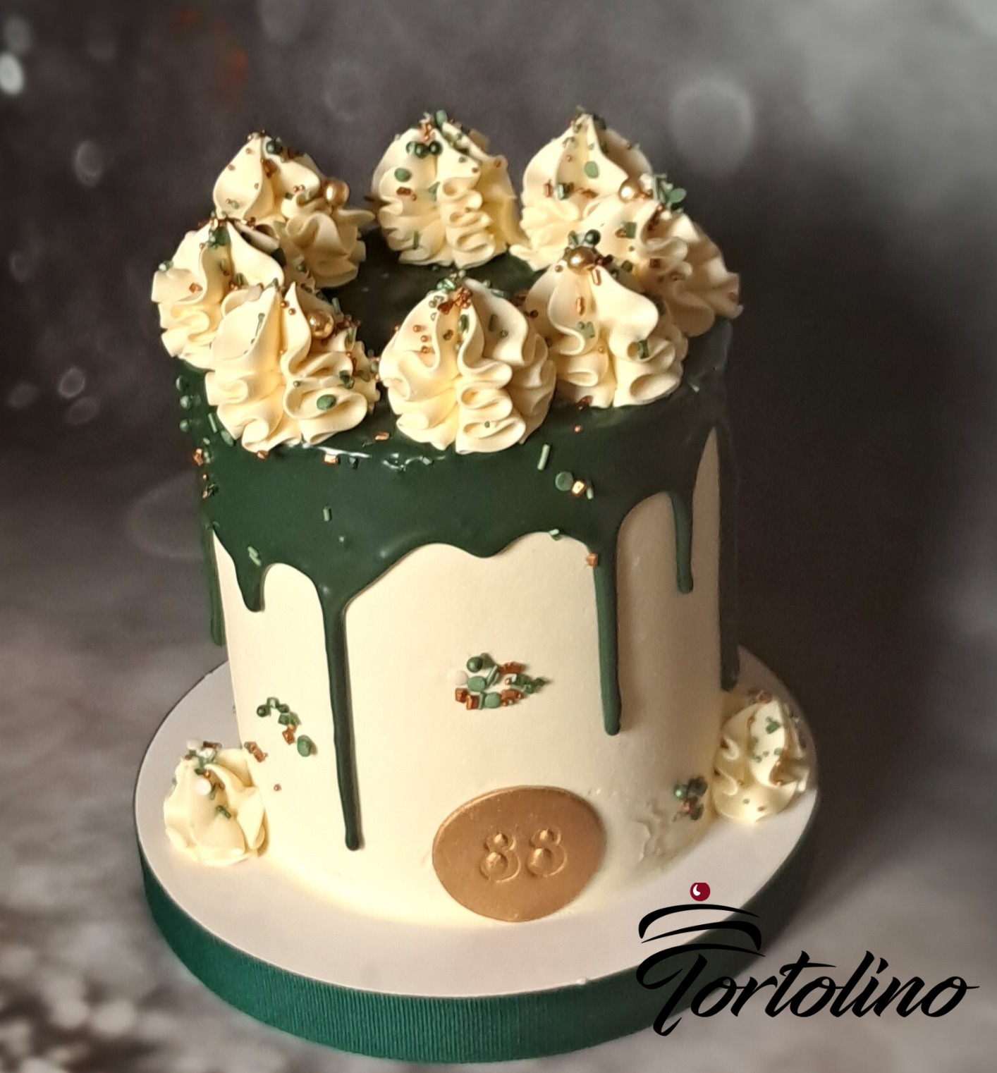 Tort urodzinowy z zielonym lukrem spływającym po bokach, kremowymi rozetkami na górze i złotą plakietką z numerem 88.
