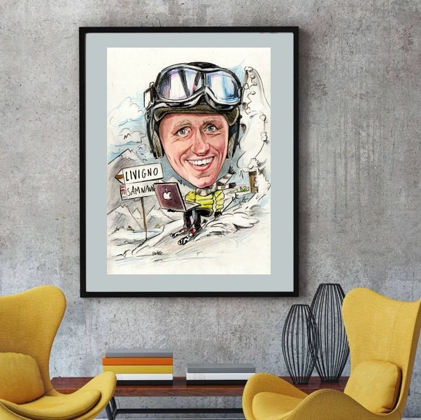Oprawiona karykatura narciarza w kasku i goglach, pracującego na laptopie Apple na stoku, z drogowskazem do Livigno i Samnaun, wisząca na ścianie nad stolikiem z dekoracjami.