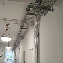 Rozprowadzenie instalacji elektrycznej w korytarzu dużego obiektu mieszkalnego, przed zabudową sufitu.