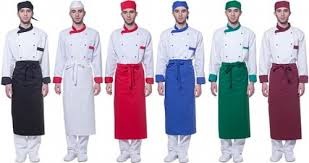 Sześciu mężczyzn w różnych kolorach fartuchów i czapkach kucharskich, prezentujących komplety uniformów, od lewej: czarny, biały, czerwony, niebieski, zielony i bordowy.