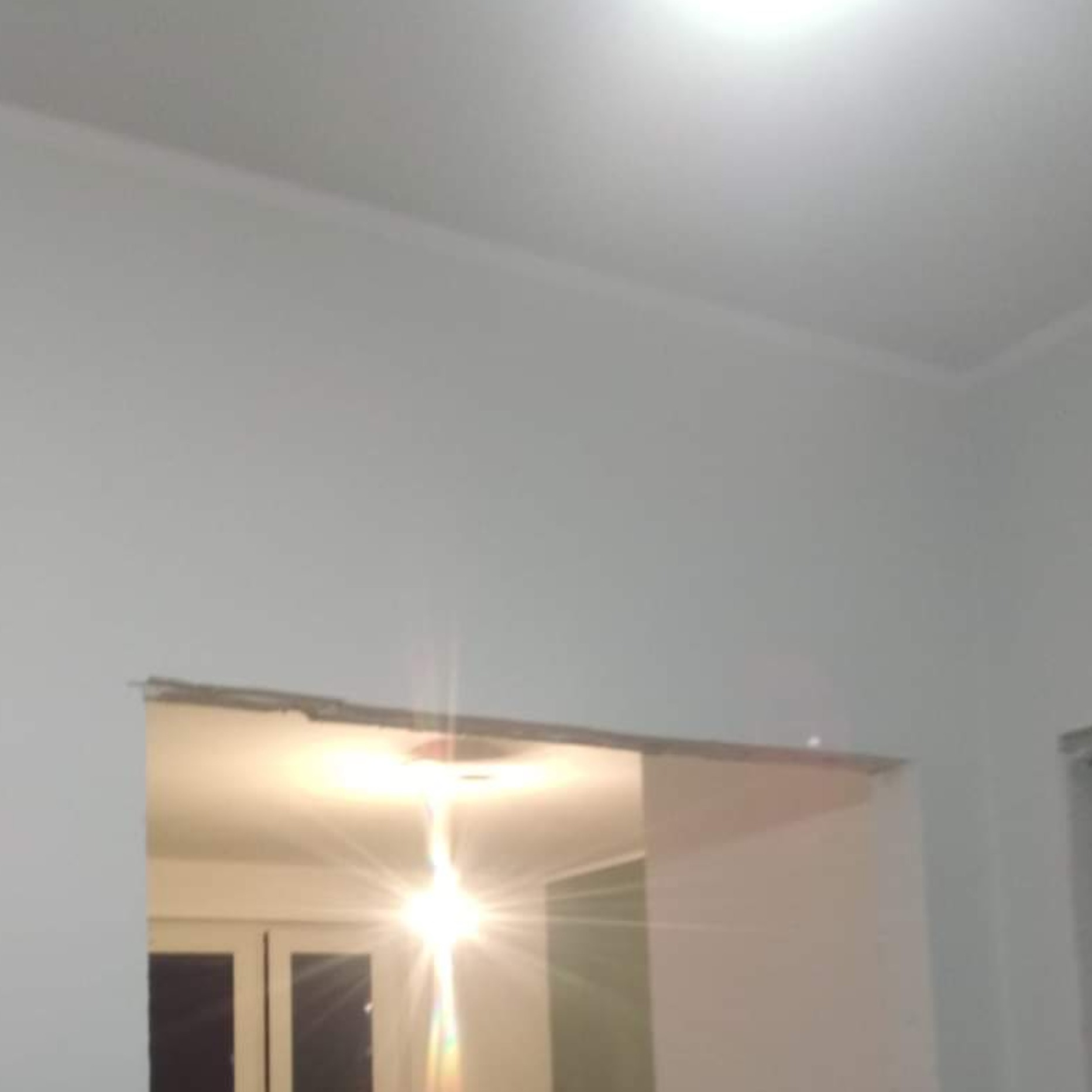 Świeżo otynkowana ściana z widocznym otworem drzwiowym, przygotowana do dalszych prac wykończeniowych.