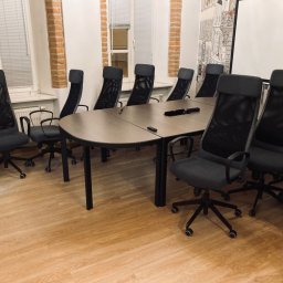 Usługi Sebastian Walczak - Sala konferencyjna z owalnym stołem i ergonomicznymi krzesłami z siatkowym oparciem, widok na okna z żaluzjami i ścianę z motywem paryskim.