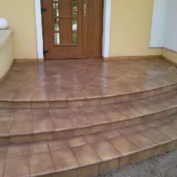 Ułożona brązowa terakota na schodach wejściowych do domu, widok z dołu.