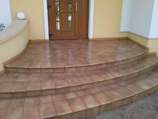 Ułożona brązowa terakota na schodach wejściowych do domu, widok z dołu.