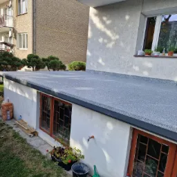 Szary taras z wykończeniem z żywicy epoksydowej, widok z góry na tle budynku mieszkalnego i zieleni.