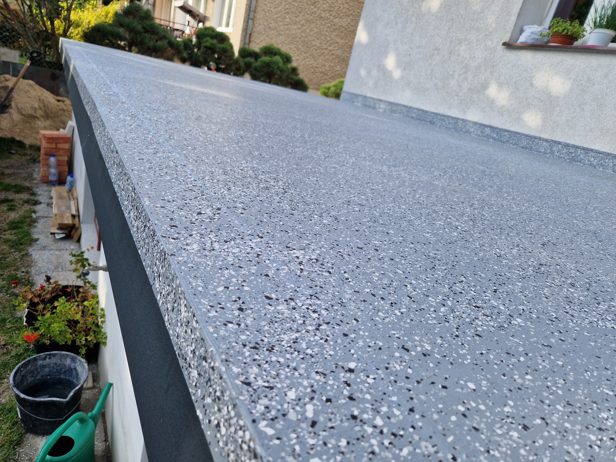 Szara, wodoodporna powierzchnia balkonu z widoczną strukturą mikrocementu, detale wykończenia oraz otoczenie budynku.