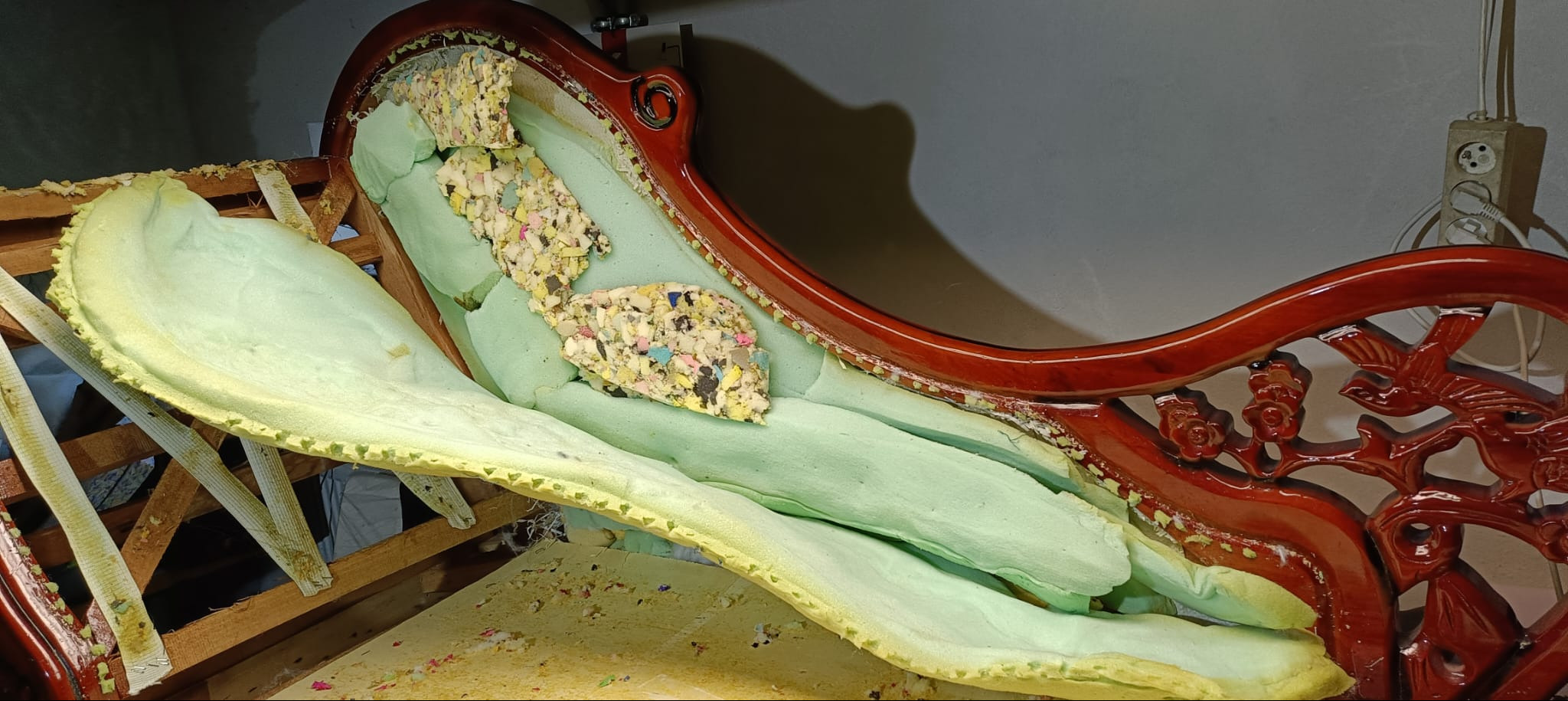 Rozłożony fotel z drewnianą ramą w trakcie renowacji. Widoczne gąbki i elementy konstrukcyjne. Ujęcie z bliska, ukazujące detale pracy.