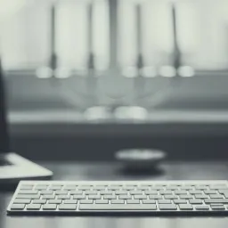 Minimalistyczne biurko z laptopem, klawiaturą i myszką na tle okna, utrzymane w monochromatycznej tonacji.