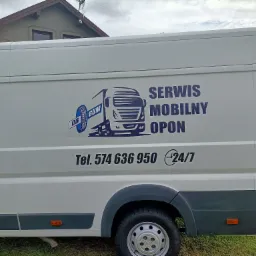 Biały samochód dostawczy z niebieskim logo i napisem 'Serwis Mobilny Opon', numer telefonu i symbol dostępności 24/7, zaparkowany na trawie przed domem.